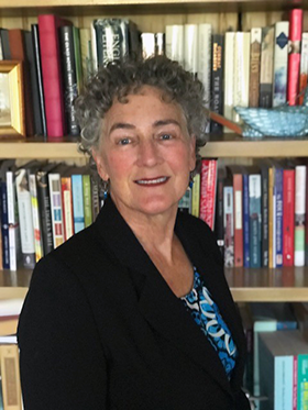 USMSM Executive Director Eileen Abel, PhD, standing in front of a bookshelf