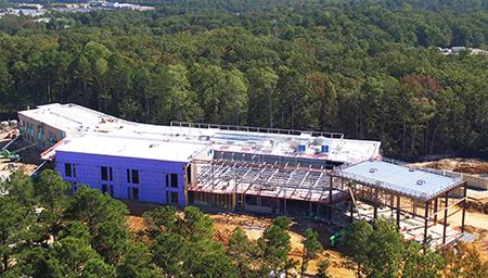 Construction site of the new SMART Building at USMSM with some exposed beams, set in a wooded areas.