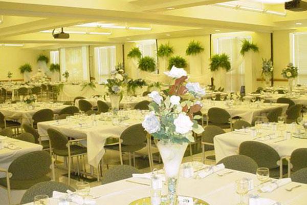Meeting room decorated for wedding with white table cloths, china and flowers